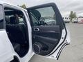 A 2018 Jeep Grand Cherokee with its front door opened showcasing the interior features and seating arrangement