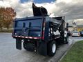 A 2011 International 7300 truck with a blue rear body and an elevated dump bed positioned at an angle