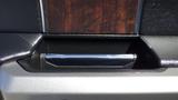 Close-up of a black and silver interior console with a wooden panel and a chrome handle in a 2017 Ford F-350 SD