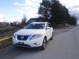 A white 2014 Nissan Pathfinder parked on a road with a sleek design and chrome accents