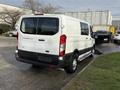 A 2023 Ford Transit van in white with a high roof and sliding side door parked on a driveway