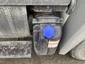 A close-up of a 2018 Hino 308's diesel exhaust fluid tank featuring a blue cap labeled DEF and a warning label attached to the tank