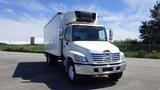 A 2009 Hino 268 truck with a white cargo box and a refrigerated unit on top parked with a clear view of the front and sides