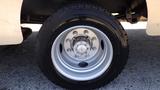 A close-up of a white wheel with eight lug nuts and a black tire featuring an all-terrain tread pattern