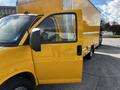 A bright yellow 2017 GMC Savana cargo van with an open side door showcasing the interior space and dashboard