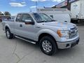 A silver 2013 Ford F-150 with chrome accents and a crew cab design parked at an angle showcasing its front and side profile