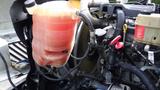 A coolant reservoir with a translucent red liquid is mounted on the engine of a 2012 International TerraStar truck