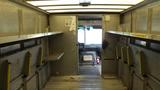 Interior view of a 2011 Ford Econoline showing metal shelving and an open doorway leading to the front cabin