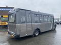 A gray 2017 Chevrolet Express shuttle bus with large windows and a rear exit door parked at a lot