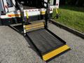 A black and yellow wheelchair lift platform is extended from the back of a 2015 Chevrolet Express van