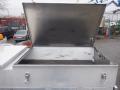 An open metal tool box with a silver finish and a hinged lid positioned on the bed of a 2009 Ford F-450 SD truck