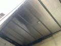 The underside of a truck bed showing metal panels and a circular light fixture