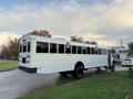 A white 2015 International 3000 school bus viewed from the rear with large windows and a flat rear end