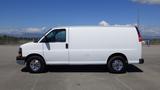 A white 2012 GMC Savana van with chrome wheels is parked with a plain side view visible