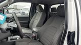 Interior of a 2016 Nissan Frontier featuring two gray fabric seats and a steering wheel. The front cabin has a practical layout with storage compartments and visibility of controls