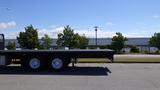 A black 2017 Freightliner M2 106 flatbed truck with dual rear wheels parked in a lot