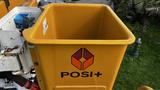 A bright yellow bucket labeled POSI+ positioned on a vehicle designed for lifting or aerial work