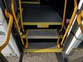 A yellow step with a textured surface positioned between two yellow handrails leading into a vehicle door of a 2015 Chevrolet Express