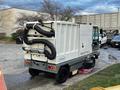 A 2007 Tennant Sentinel street sweeper with a white chassis and black hoses attached to the rear, designed for efficient outdoor cleaning tasks