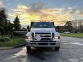 A 2006 Ford F-650 truck with a front-mounted snow plow and chrome grille parked on a paved area