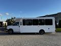 A 2017 Chevrolet Express passenger bus with a white exterior and large tinted windows, featuring a raised roof and side entry door