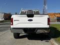 A white 2017 Ford F-150 truck viewed from the rear with a metal ladder rack above the bed and the Ford emblem prominently displayed on the tailgate