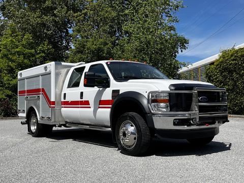 A white 2009 Ford F-550 truck with red and silver accents features a service body and dual rear wheels parked at an angle