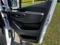 A close-up of the door panel of a 2022 Mercedes-Benz Sprinter featuring a black plastic surface with a handle and a small storage compartment