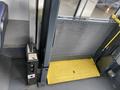 A 2018 Chevrolet Express bus door opening mechanism featuring a yellow platform and a black control box with a lever and operational labels