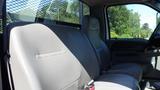 Interior view of a 2006 Ford F-650 showing a gray cloth bench seat with seat belts and a console, highlighting the spaciousness of the cab