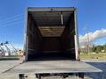 A 2013 International 4300 truck with an empty cargo area visible from the rear with wooden interior walls and a flat loading platform