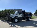 A 2007 International 7300 truck equipped with a snowplow attachment and a large rear storage compartment for snow or other materials