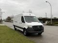 A white 2019 Mercedes-Benz Sprinter van parked on the side of the road with a sleek design and the iconic Mercedes logo on the front grille