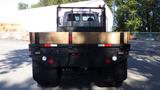 A 2007 Sterling Acterra L7500 truck with a black rear and wooden flatbed featuring a mesh guard and red and white reflective markings