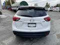 A rear view of a white 2016 Mazda CX-5 showcasing its taillights and rear badge without any visible license plate details