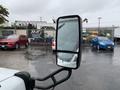 A 2015 Chevrolet Express van with a large side mirror reflecting a rainy scene and additional vehicles parked nearby