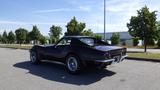 A 1971 Chevrolet Corvette Stingray in dark paint with a sleek design and distinct rear lights showcasing its classic styling