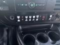 The dashboard of a 2017 Chevrolet Express featuring various control buttons and knobs along with dual cup holders