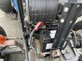 A close-up view of the engine compartment of a 2007 New Holland TN70A tractor showing the battery and various components