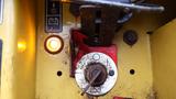 A close-up view of a control panel featuring a red and white circular dial with a rusted key slot and an illuminated yellow indicator light