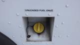 A fuel filler neck with a yellow cap labeled unleaded fuel only