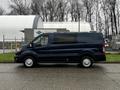 A side view of a dark blue 2020 Ford Transit van with a long wheelbase and large windows