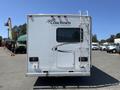 A white 2012 Ford Econoline motorhome with a ladder on the back and a window in the center