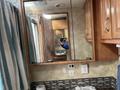 2008 Newmar Canyon Star 36 Foot Class A Motorhome reflecting in a bathroom mirror with wooden cabinets and a tiled backsplash