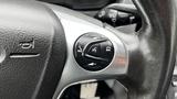 Close-up of a steering wheel control panel featuring buttons for volume, phone, and audio settings on a 2017 Ford Transit