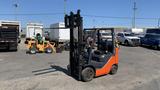 A 2018 Toyota 8FGCU25 forklift with an orange and black design and a vertical lifting mechanism positioned in a parking area