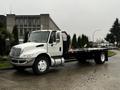 A white 2011 International DuraStar 4300 flatbed truck with a black flatbed and mesh safety guard