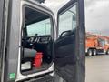 Interior view of a 2018 Hino 308 truck with open door displaying the driver's seat dashboard and a red bucket on the floor