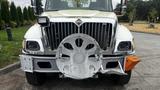 A 2006 International 7500 truck with a shiny chrome grille and a circular metal guard attached to the front bumper