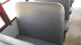 The image shows the backrest of a gray school bus seat with a simple textured surface and no visible wear